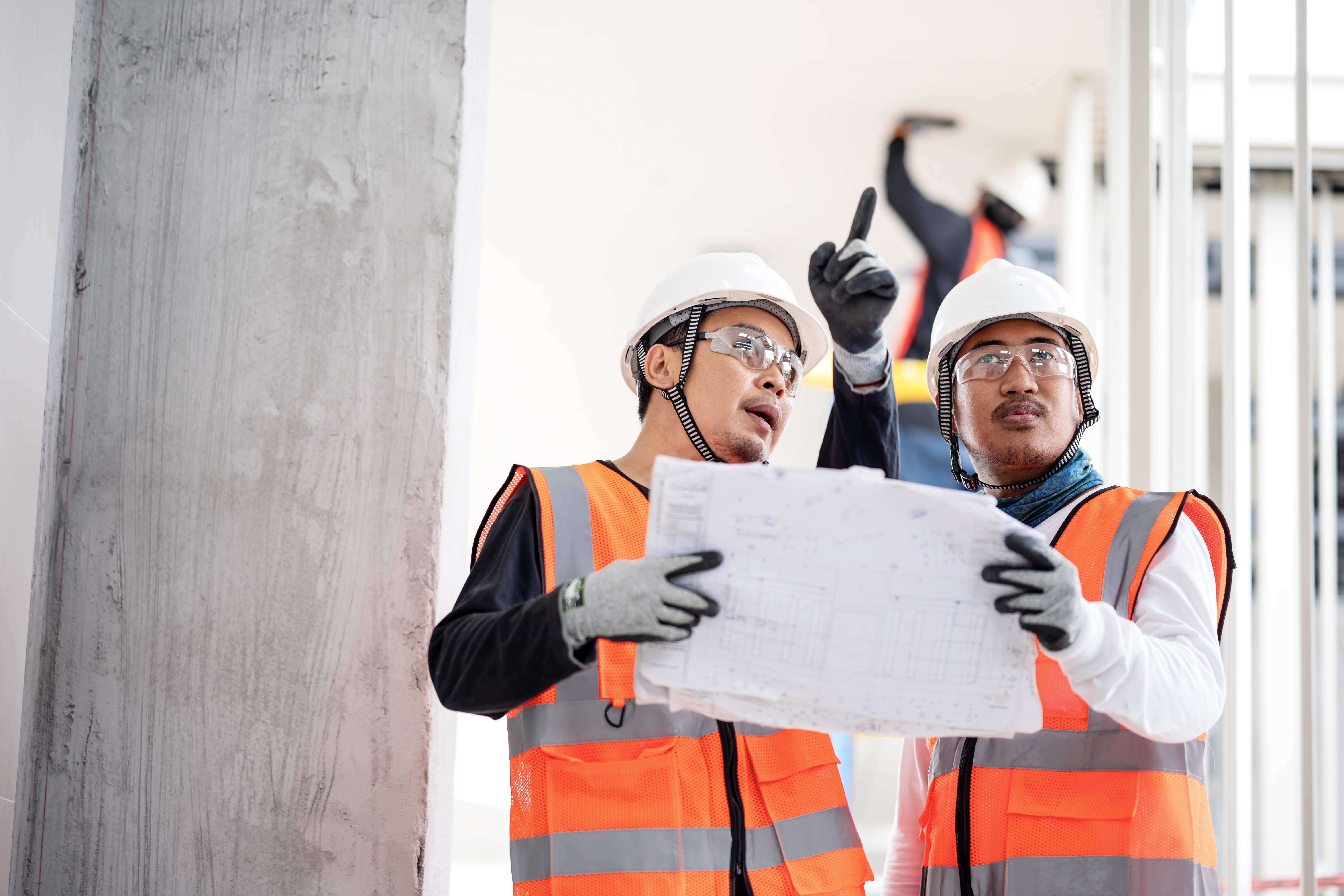 Construction engineers discuss a blueprint or project task details
